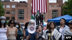 People speak to the press as they gather at an encampment to support the people of Palestine during a protest at George Washington University, May 6, 2024, in Washington.