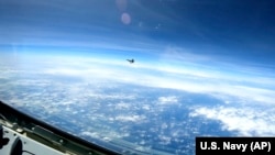 En esta imagen de un video proporcionado por la Armada de EEUU, un caza J-16 chino vuela cerca de un avión RC-135 de EEUU que vuela en el espacio aéreo internacional sobre el Mar de China Meridional el 26 de mayo de 2023. (Marina de EEUU/AP)