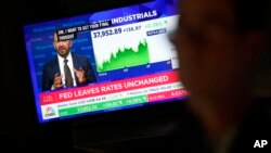 A screen displays news about interest rates as traders work on the floor at the New York Stock Exchange in New York, May 1, 2024. 