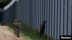 FILE - Polish soldiers patrol along a border fence on the Polish-Belarusian border, in Usnarz Gorny, Poland, Aug. 30, 2023.