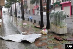 Puing-puing berserakan di jalanan pusat kota Naha, prefektur Okinawa, saat angin kencang yang dipicu oleh Topan Khanun menghantam kota itu, 2 Agustus 2023. (JIJI Press / AFP)