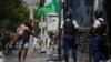 FILE - A parent, holding his child, runs past police carrying out an operation against gangs in the Bel-Air area of Port-au-Prince, Haiti, March 3, 2023. Prime Minister Ariel Henry signaled March 17, 2023 that he wants to mobilize Haiti's military to help fight the gangs. 