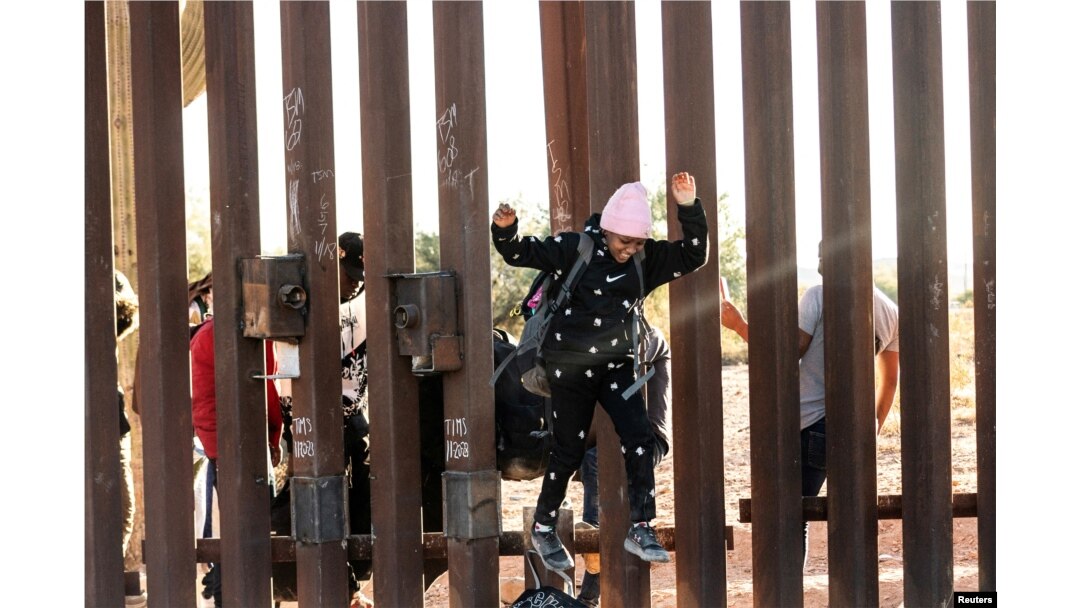 FILE - A migrant child jumps to cross into the U.S. from Mexico through a gap in the border wall, in Lukeville, Arizona, Dec. 12, 2023.
