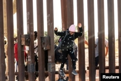 FILE - A migrant child jumps to cross into the U.S. from Mexico through a gap in the border wall, in Lukeville, Arizona, Dec. 12, 2023.