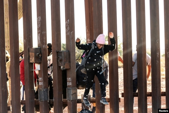 FILE - A migrant child jumps to cross into the U.S. from Mexico through a gap in the border wall, in Lukeville, Arizona, Dec. 12, 2023.