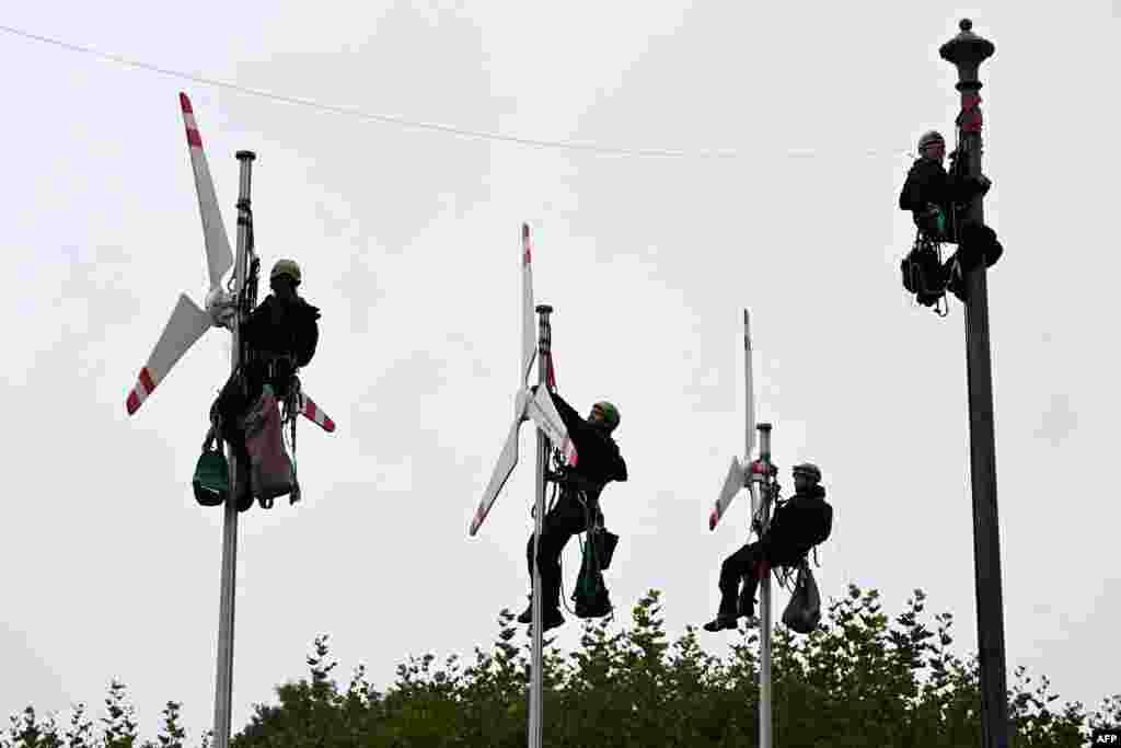 Greenpeace activists climb up flagpoles to fix mockups of wind turbines in front of the Bavarian State Chancellery in Munich, Germany, as they call for more wind power. 