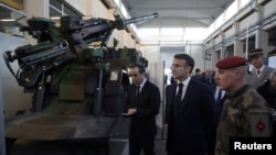 French President Emmanuel Macron inspects a Caesar artillery system during a visit to the Cherbourg naval base as part of his New Year's wishes to the French army, in Cherbourg, northwestern France, 19 Jan. 2024.