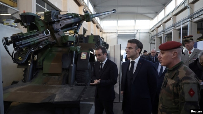 French President Emmanuel Macron inspects a Caesar artillery system during a visit to the Cherbourg naval base as part of his New Year's wishes to the French army, in Cherbourg, northwestern France, 19 Jan. 2024.