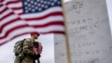 A member of the 3rd U.S. Infantry Regiment, also known as The Old Guard, places flags in front of each headstone for "Flags-In" at Arlington National Cemetery in Arlington, to honor the Nation's fallen military heroes ahead of Memorial Day.