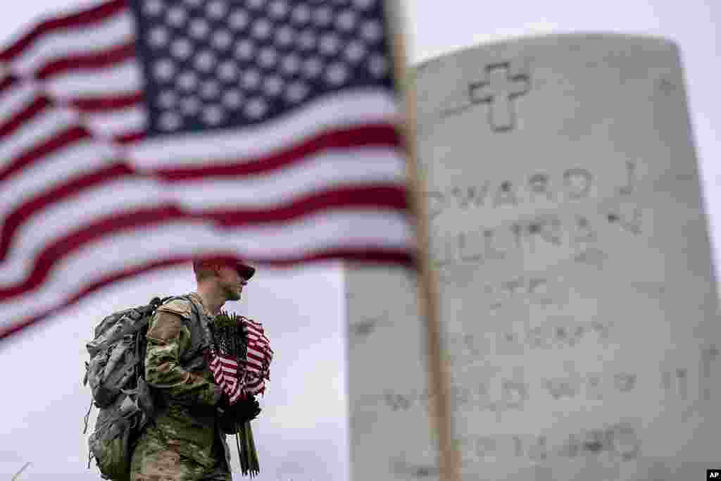 A member of the 3rd U.S. Infantry Regiment, also known as The Old Guard, places flags in front of each headstone for "Flags-In" at Arlington National Cemetery in Arlington, to honor the Nation's fallen military heroes ahead of Memorial Day.