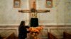 Una mujer adorna una imagen religiosa con flores de caléndula mexicana en la iglesia del cementerio municipal de Arocutin Michoacán, el domingo 31 de octubre de 2021.
