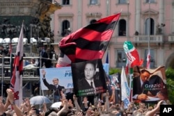 People wave banners in front of Milan's Gothic Cathedral for former Italian premier Silvio Berlusconi's state funeral, in Italy, June 14, 2023.