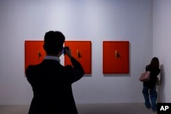 FILE - Visitors look at an artwork titled "Possibility 023-CII, CIII, CIV," created by Korean artist Song Burnsoo at the Art Basel during a preview in Hong Kong, March 21, 2023.