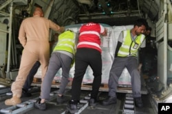 A team from King Salman Humanitarian Aid and Relief Centre push a load of relief supplies, inside a Saudi military C130 plane before it takes off from King Khalid airport to Port Sudan, in Riyadh, Saudi Arabia, May 10, 2023.