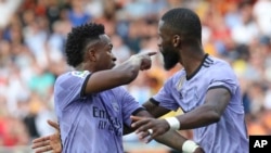 Real Madrid's Vinicius Junior, left, confronts Valencia fans as Antonio Rudiger tries to calm him down during a Spanish La Liga soccer match between Valencia and Real Madrid, at the Mestalla stadium in Valencia, Spain, May 21, 2023. 