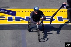 Marcel Hug of Switzerland breaks the tape to win the men's wheelchair division at the Boston Marathon in Boston, April 15, 2024.