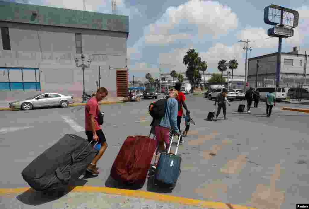 Migrantes de Rusia y Haití caminan hacia el puente fronterizo internacional de Hidalgo luego de recibir una cita para asilo en Estados Unidos usando la aplicación CBP ONE.