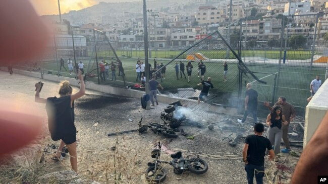 Residents rush to help injured children moments after a rocket attack hit a soccer field in the Druze town of Majdal Shams in the Israeli-controlled Golan Heights, July 27, 2024.