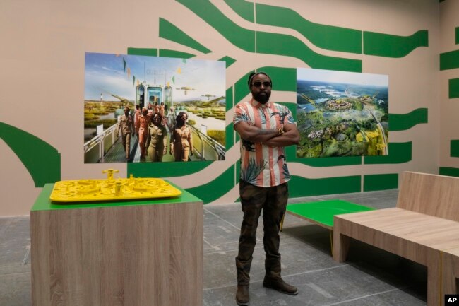 Nigeria's Olalekan Jeyifous poses next to his creations, at the Biennale International Architecture exhibition, in Venice, Italy, May 17, 2023.