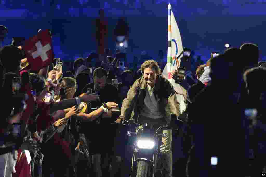 Tom Cruise rides a motorbike with the Olympic flag attached during the 2024 Summer Olympics closing ceremony at the Stade de France, Aug. 11, 2024, in Saint-Denis, France.