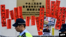 FILE - Police walk past messages in support of jailed Chinese human rights lawyer Wang Quanzhang (pictured at right on placard) outside the Chinese Liaison Office in Hong Kong, Jan. 29, 2019.