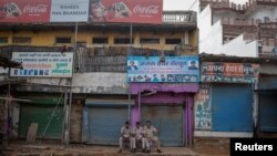 Polisi duduk di luar toko-toko yang tutup selama jam malam yang diberlakukan oleh pihak berwenang menyusul bentrokan antara umat Hindu dan Muslim di distrik Nuh di negara bagian utara Haryana, India, 1 Agustus 2023. (Foto: REUTERS/Adnan Abidi)