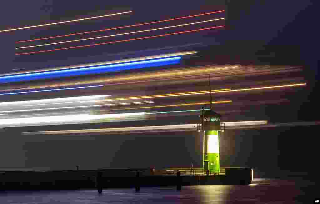 A ferry passes a small lighthouse at the entrance of the harbor in Travemuende, northern Germany.