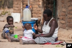 FILE - Children eat porridge prepared at a feeding center in Mudzi, Zimbabwe, on July 2, 2024. In Zimbabwe, an El Nino-induced drought is affecting millions of people, and children are most at risk.