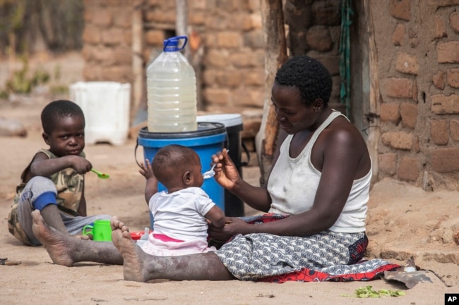 FILE - Children eat porridge prepared at a feeding center in Mudzi, Zimbabwe, on July 2, 2024. In Zimbabwe, an El Nino-induced drought is affecting millions of people, and children are most at risk.