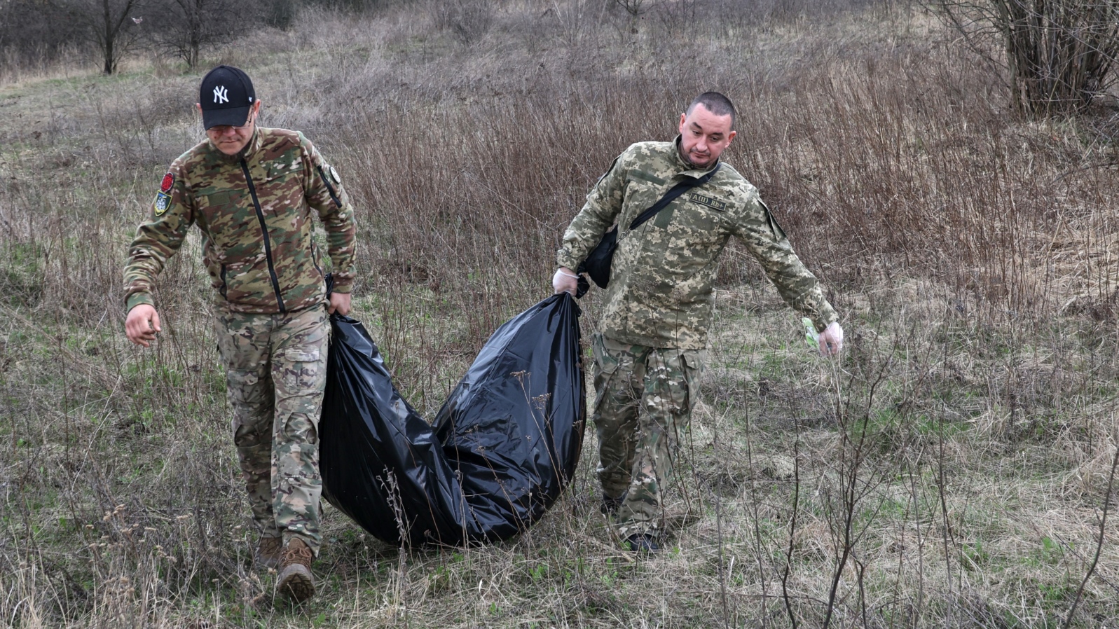 Miembros de un equipo ucraniano especial retiran los restos de un soldado ruso encontrado en la aldea de Synykha, en la región de Járkov, el 8 de abril de 2023.