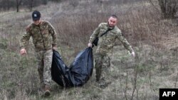 Miembros de un equipo ucraniano especial retiran los restos de un soldado ruso encontrado en la aldea de Synykha, en la región de Járkov, el 8 de abril de 2023.