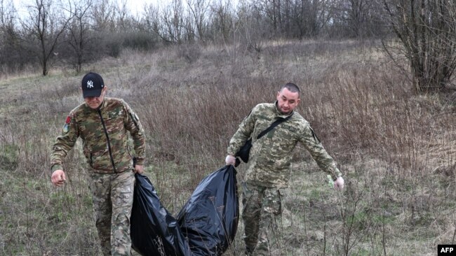 Members of a Ukrainian Civil-Military Cooperation team carry the remains of a Russian soldier in the village of Synykha, in Ukraine's Kharkiv region, April 8, 2023.