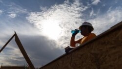 FILE - Seorang pekerja konstruksi minum minuman dingin saat gelombang panas mencapai lebih dari 110 derajat Fahrenheit di Scottsdale, Arizona, 28 Juli 2023. Sebuah studi baru mengatakan perubahan iklim akan memangkas pendapatan dan juga berdampak pada produktivitas pekerja.