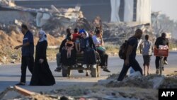 Palestinos toman la carretera en Al-Maghazi mientras huyen de sus campamentos de desplazados debido a los intensos bombardeos israelíes sobre el centro de la Franja de Gaza el 5 de junio de 2024.