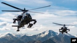 FILE - In this photo released by the US Army, AH-64D Apache Longbow attack helicopters from the 1st Attack Battalion, 25th Aviation Regiment, fly over a mountain range near Fort Wainwright, Alaska, on June 3, 2019.