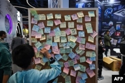 A boy leaves a message on a board next to a display for the book "The Three- Body Problem" at the 2023 World Science Fiction Convention in Chengdu, China, Oct. 21, 2023.