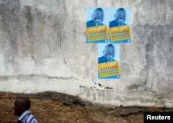 FILE - A man walks past election posters for Zacharie Myboto, one of the 23 declared presidential candidates for Sunday's poll, in the capital Libreville, August 22, 2009.