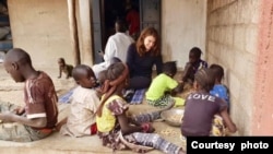 Audrey Gray, recipient of a Kim Wall Memorial Fund grant, sits with children in Senegal as they sort peanuts to sell. The American journalist was in Senegal covering climate adaption measures on Jan. 4, 2019. (Photo courtesy of Audrey Gray)