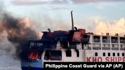 In this handout photo provided by the Philippine Coast Guard, smoke comes out from Philippine ferry M/V Esperanza Star as it caught fire at the waters off Panglao, Bohol province, central Philippines on Sunday, June 18, 2023 (Philippine Coast Guard via AP)