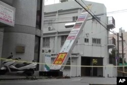 Papan toko yang miring akibat hempasan Topan Khanun, di Naha, prefektur Okinawa, 3 Agustus 2023. (NTV via AP)