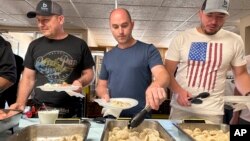 Maksym Bunchukov, Andrii Hryshchuk and Ivan Sakivskyi help themselves to perogies at a lunch hosted, July 17, 2023, by the Ukrainian Cultural Institute in Dickinson, North Dakota. 