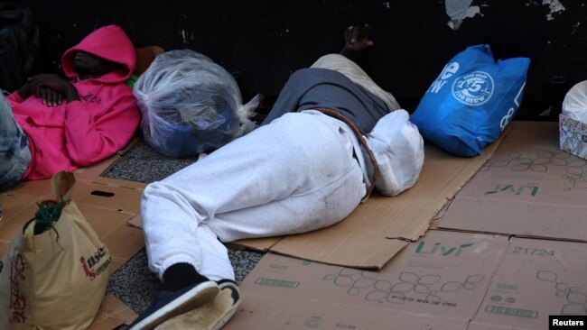 New York'a yeni gelen göçmenler, New York'ta geçici bir kabul merkezinin kurulduğu Manhattan'da kaldırımda karton çarşafların üzerinde uyuyorlar.