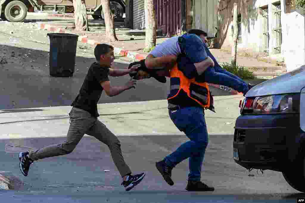 A medical worker carries an injured man to safety during clashes between Israeli forces and Palestinians following an Israeli army raid in the occupied West Bank city of Nablus.