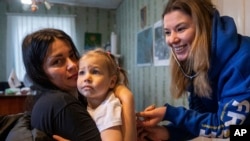 Una voluntaria médico de FRIDA Ucrania escucha a través de un estetoscopio los pulmones de una niña mientras brinda atención médica especializada a civiles en la aldea de Khrestysche, región de Donetsk, Ucrania, el domingo 19 de marzo de 2023.