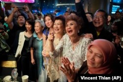 Ibu Michelle Yeoh, Janet Yeoh dan kerabatnya sedang menyaksikan putrinya memenangkan Piala Oscar. (Foto AP/Vincent Thian)