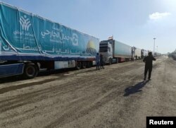 An Egyptian volunteer walks next to trucks carrying humanitarian aid from Egyptian NGOs for Palestinians, as they await for the reopening of the Rafah crossing at the Egyptian side to enter Gaza, in Rafah, Egypt, Oct. 19, 2023.