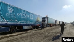 2023年10月19日，一名埃及志愿者走在载有埃及非政府组织为巴勒斯坦人提供的人道主义援助物资的卡车旁边。（路透社照片）