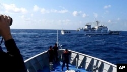 资料照：菲律宾海岸警卫队发布照片显示，一艘中国海警船（上）正在有争议的南中国海阻拦一艘菲律宾政府船只登陆铁线礁（Sandy Cay ）。（2024年3月21日）