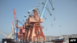 FILE - Pakistani laborers walk through the Gwadar, Pakistan, port on Oct. 4, 2017.