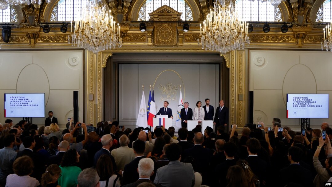 France's President Emmanuel Macron gives a speech next to International Olympic Committee (IOC) President Thomas Bach and others during a reception for international journalists accredited for the Paris 2024 Olympic Games, July 22, 2024. 
